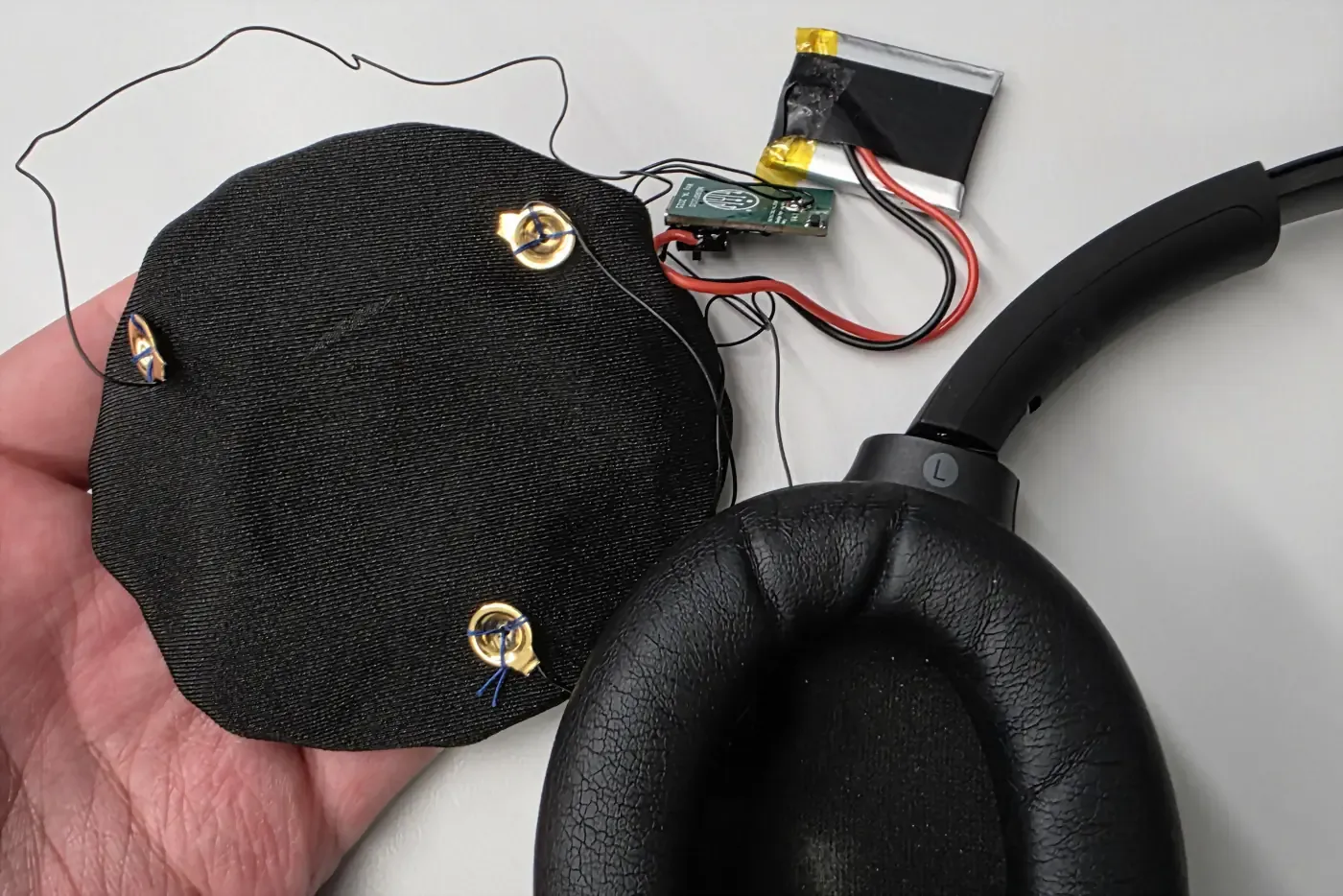 An earpad with the dry electrodes wired in, next to the cup it sits in